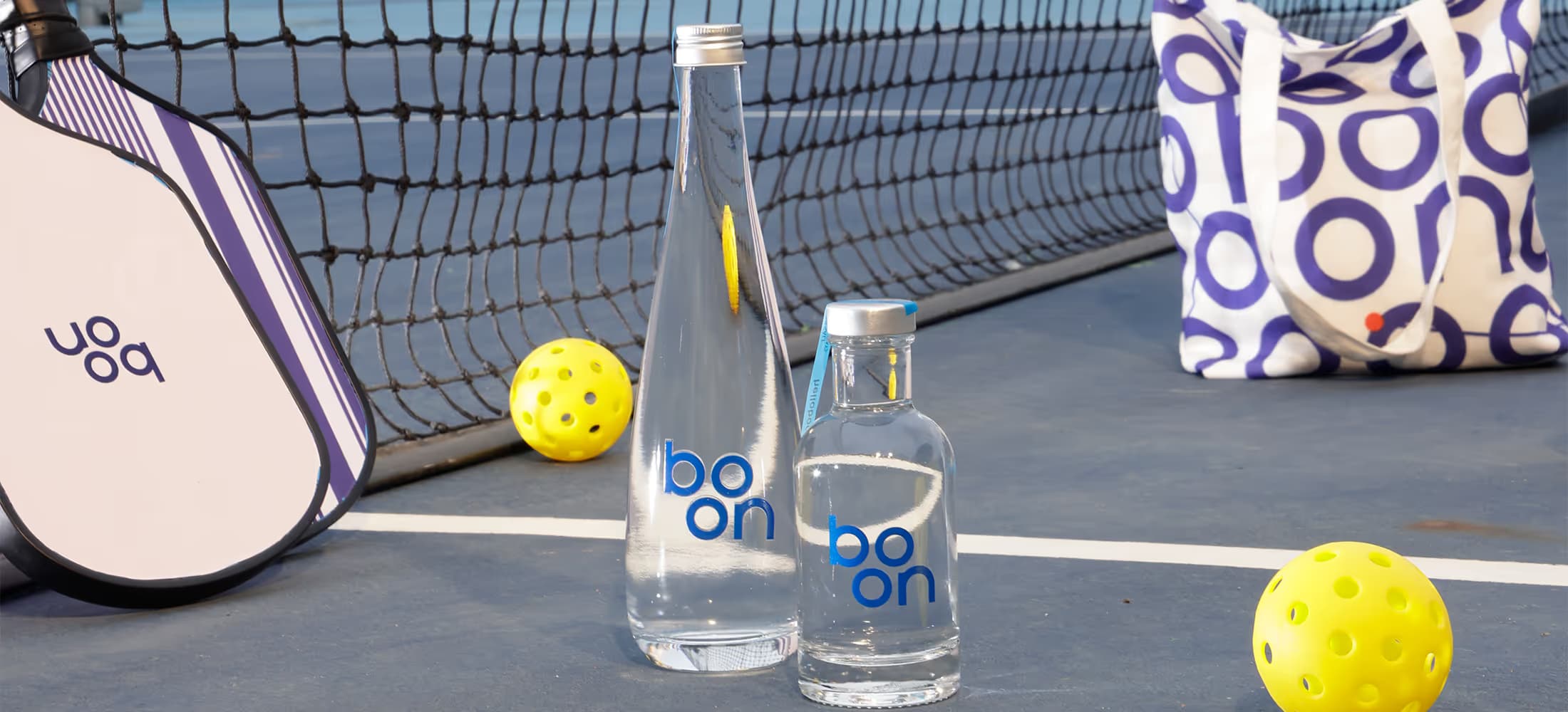 Boon glass bottles courtside at a tennis game