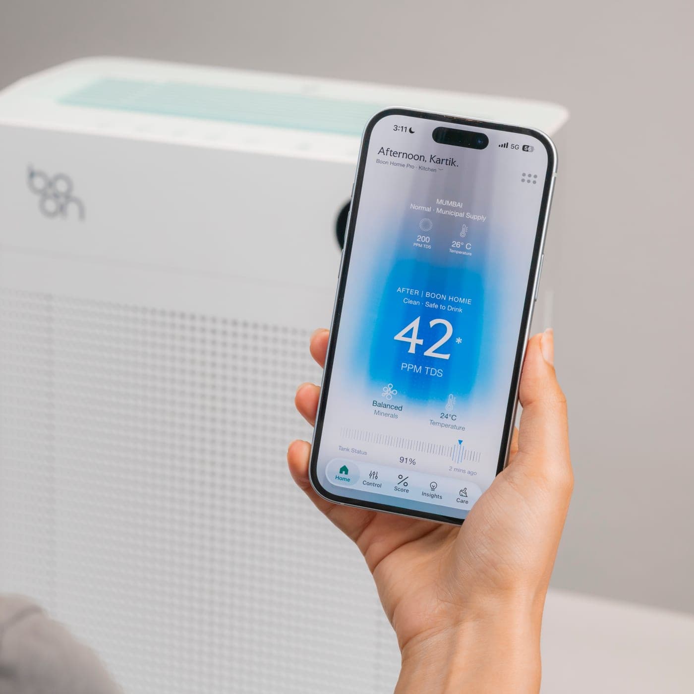 A woman holding up the Boon app beside Boon Airvana™