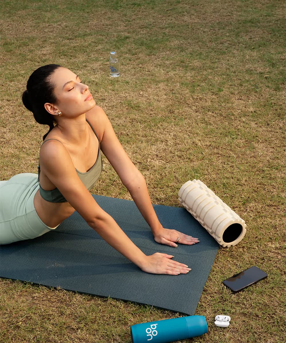 Woman on a yoga mat with a Boon glass bottle