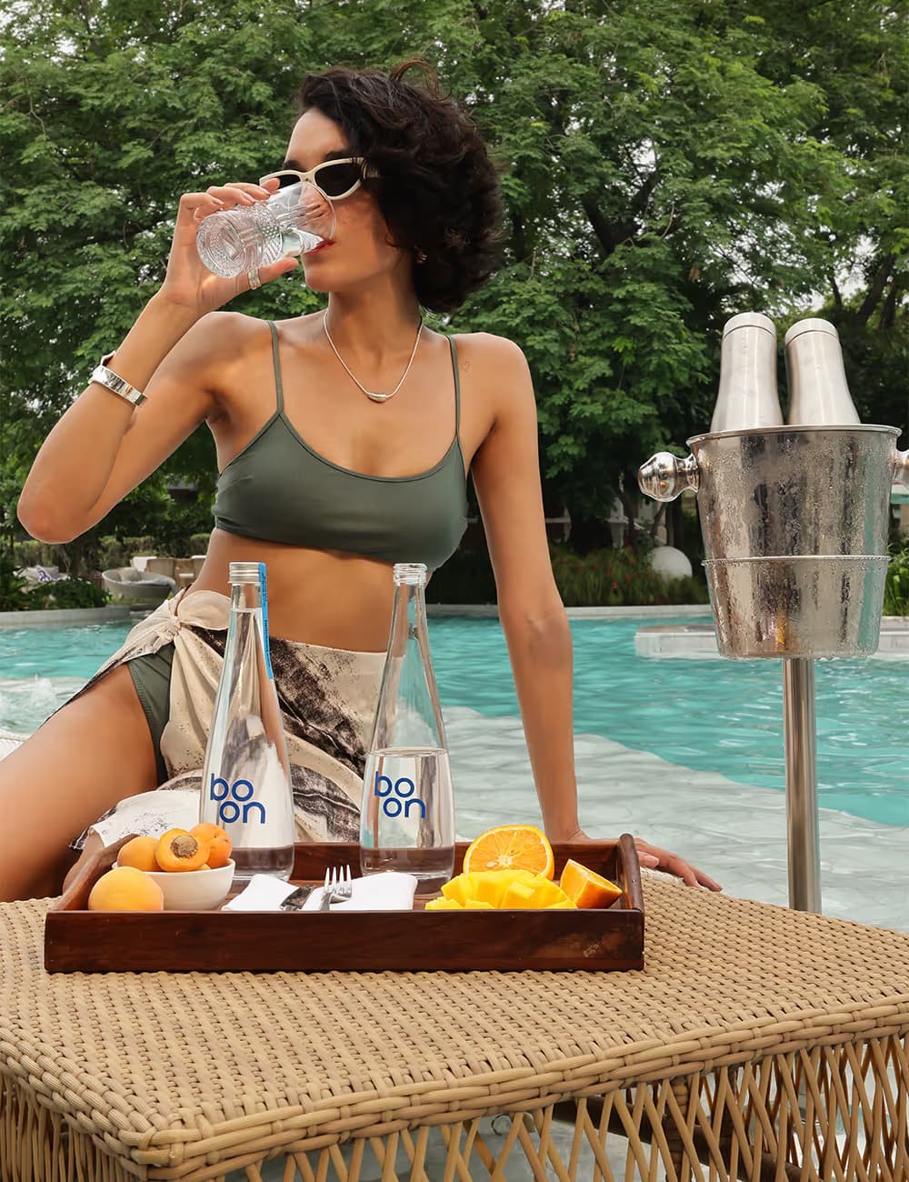 A lady drinking from a Boon glass bottle