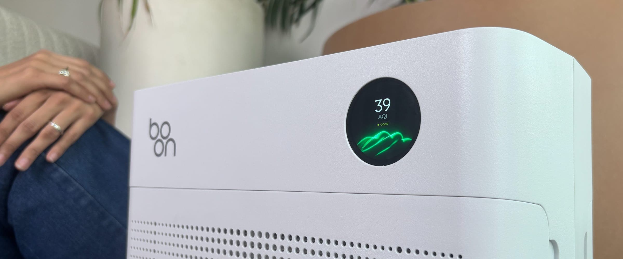 Boon Airvana™ beside a seated person, its display reading AQI 39